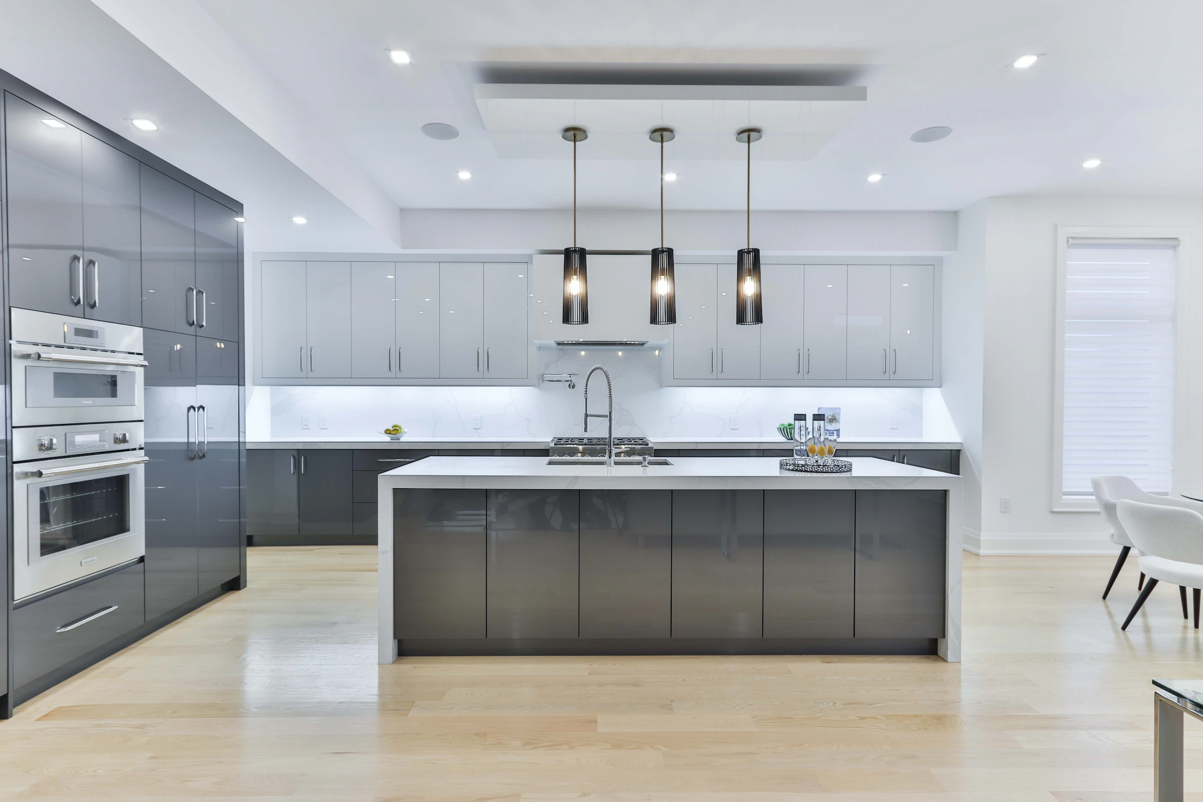 Open kitchen with a recessed ceiling, spotlights and three pendant lights over an island