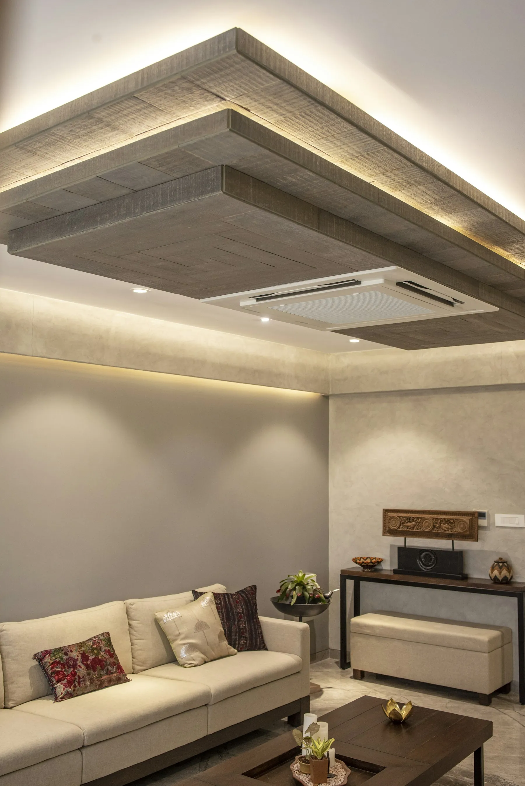 Living room with a layered false ceiling and warm cove lighting around its edge