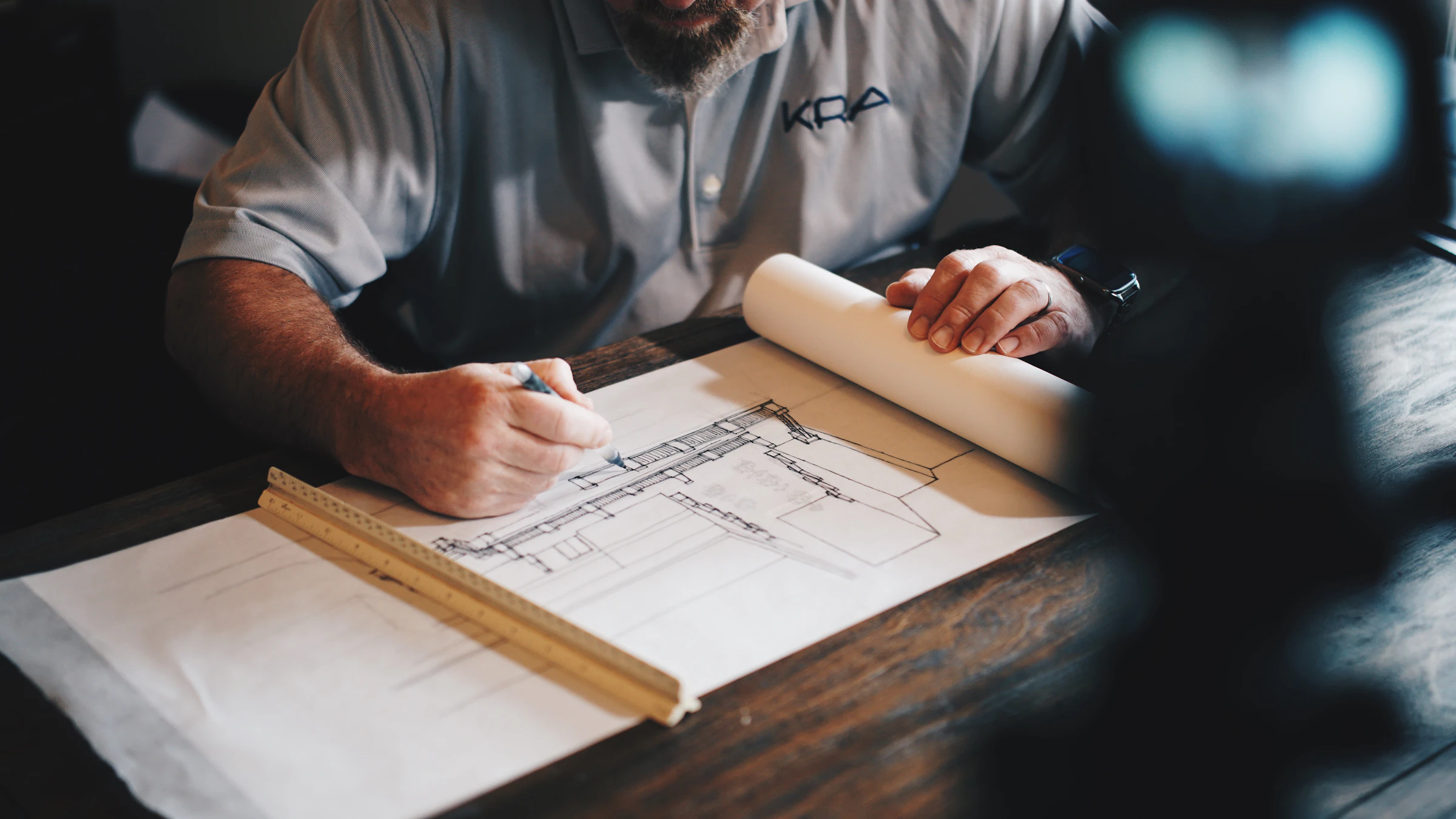 Designer drawing a floor plan by hand with a scale ruler