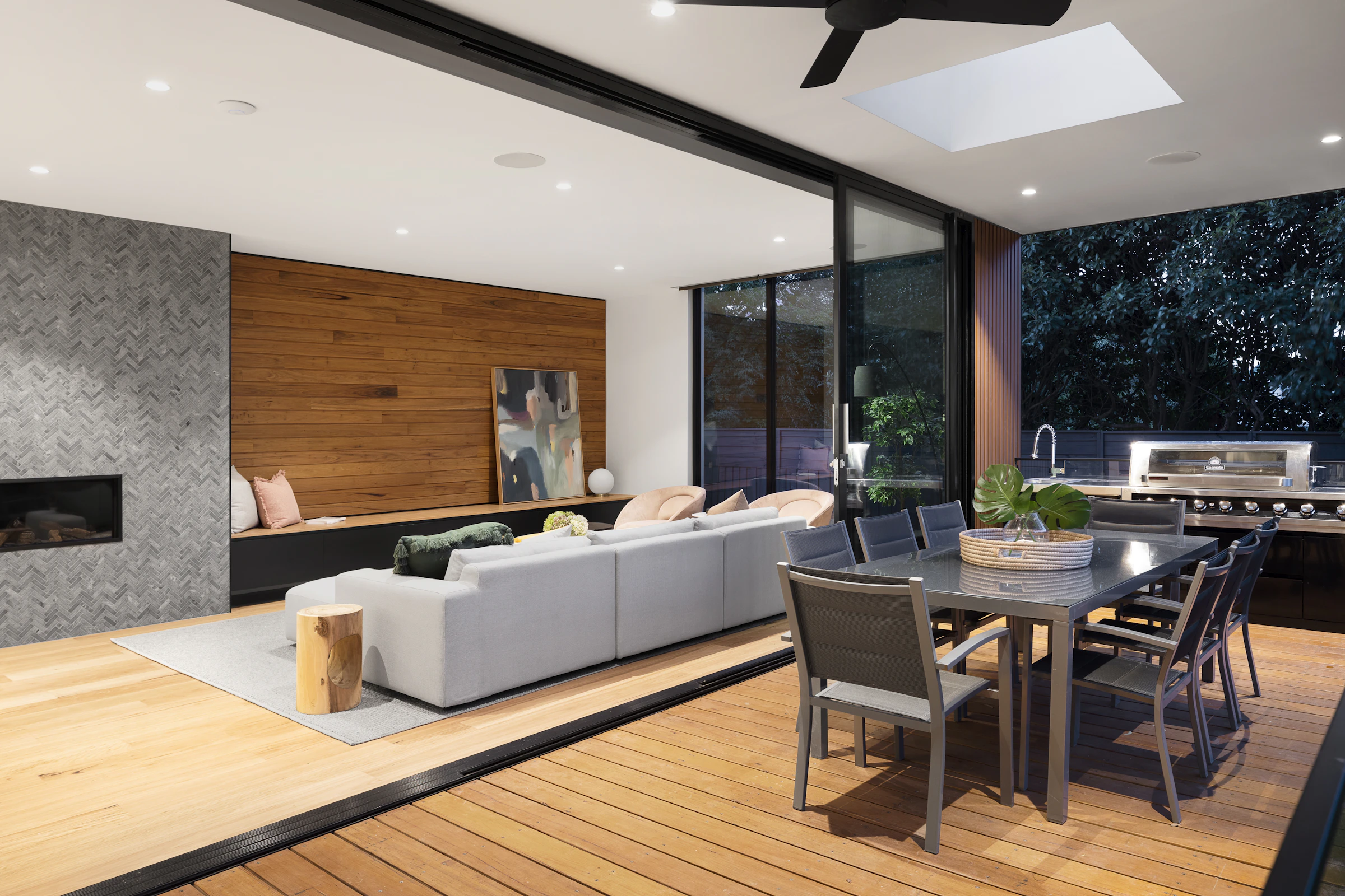 Open-plan living and dining room opening onto a deck in the evening