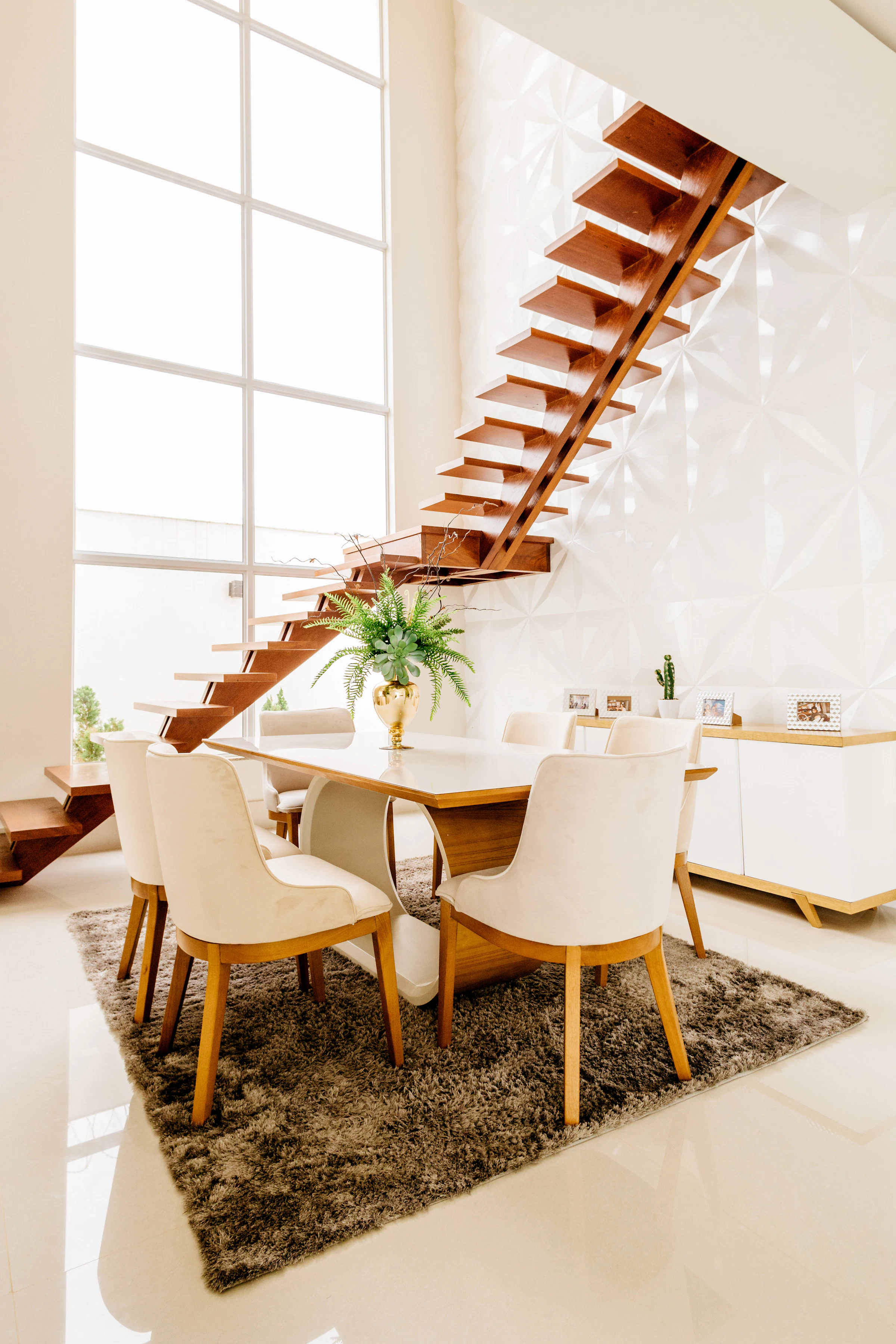 Double-height dining room beside an open timber staircase