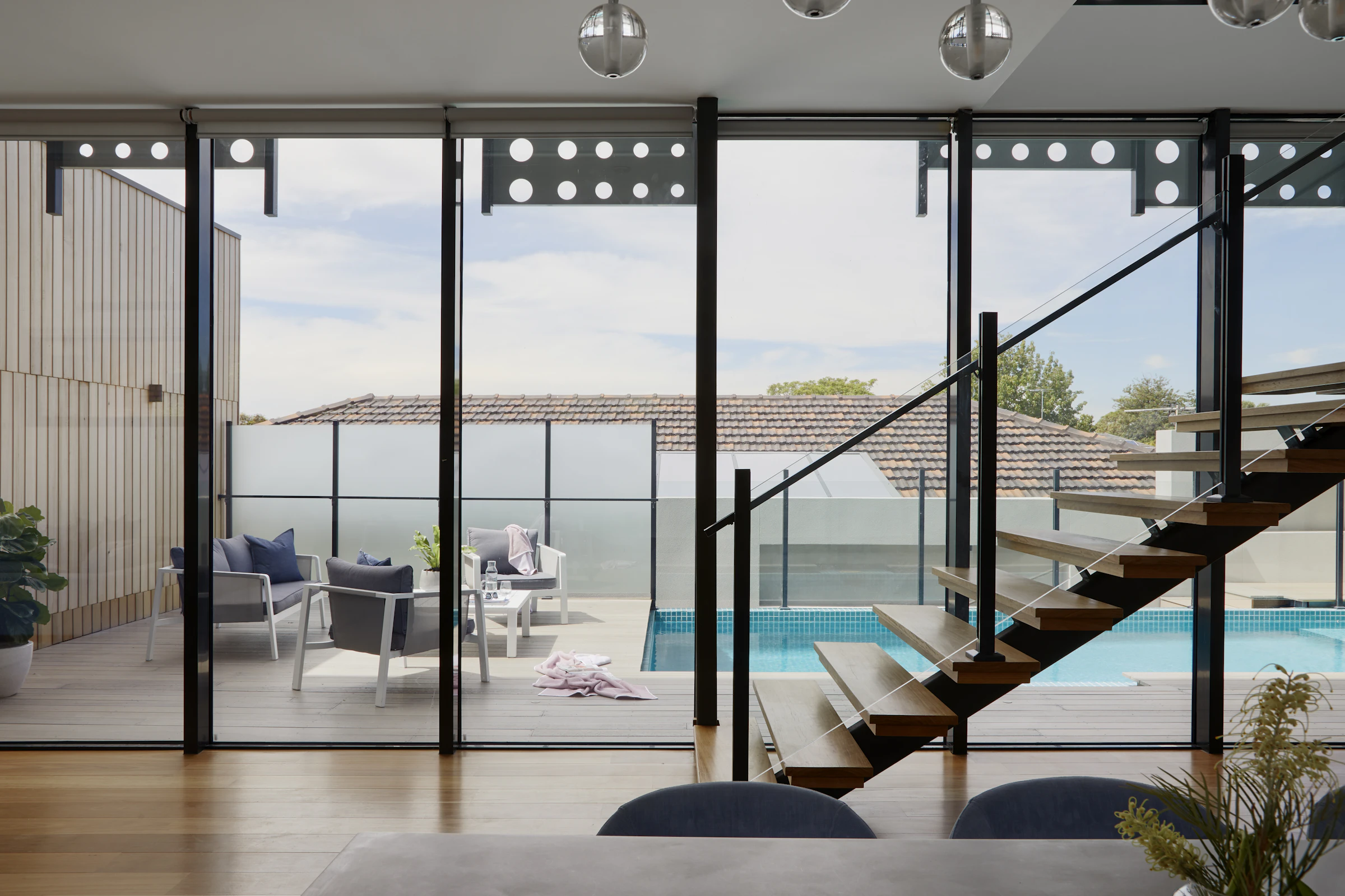 Open staircase with steel stringers beside full-height glass doors
