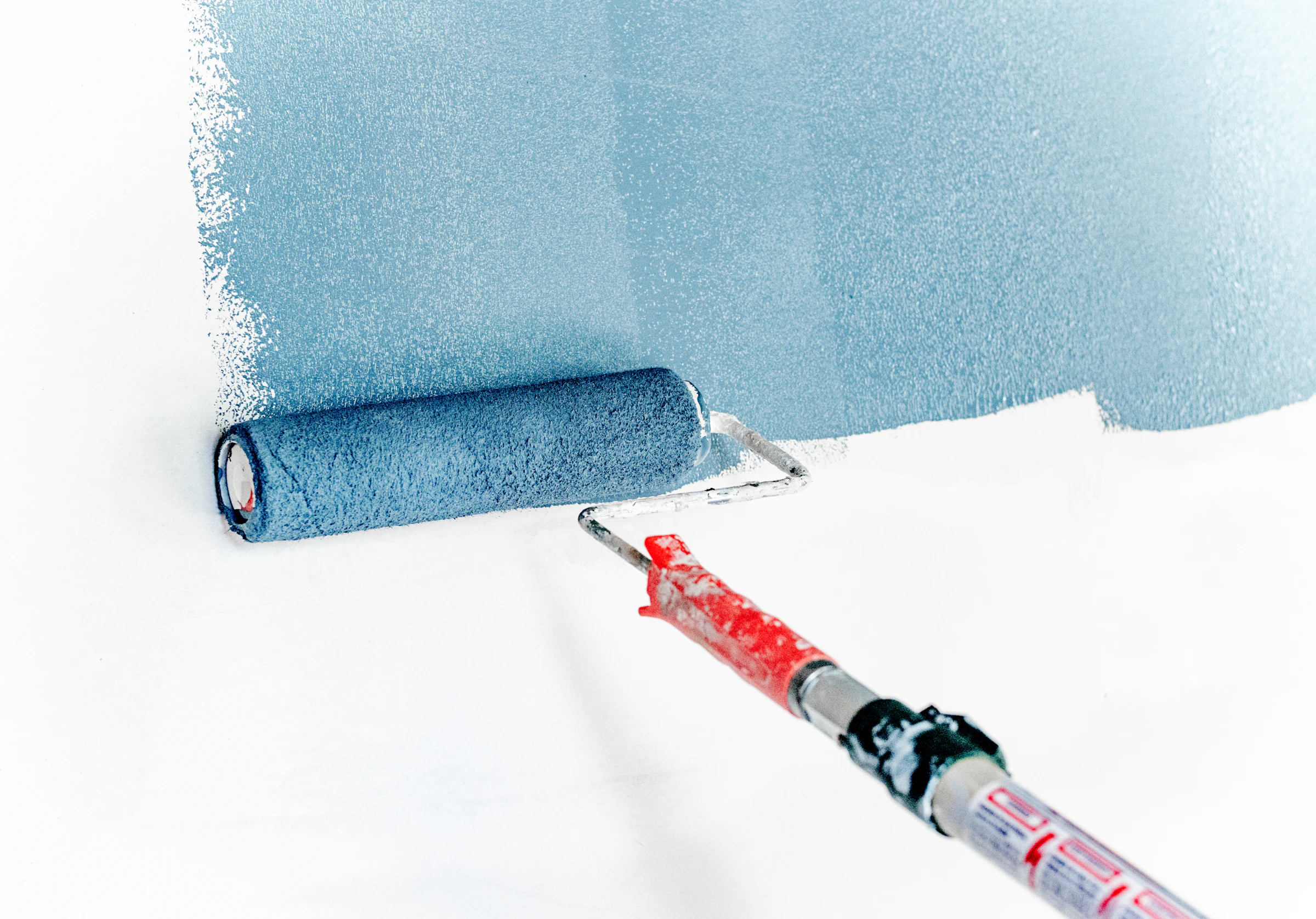 Paint roller laying a fresh coat of colour on a white wall