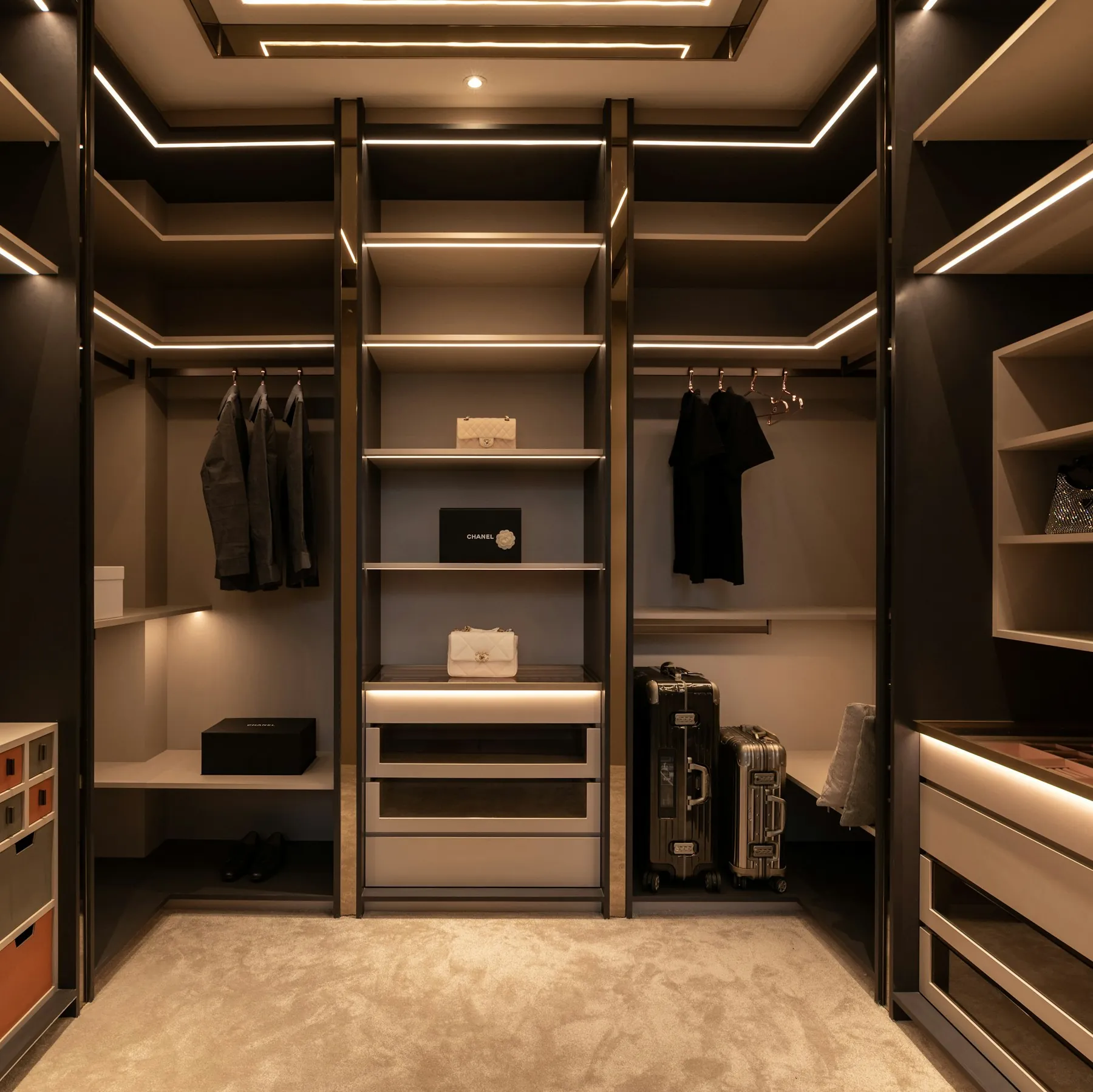 Walk-in wardrobe with open hanging rails, drawers and warm strip lighting