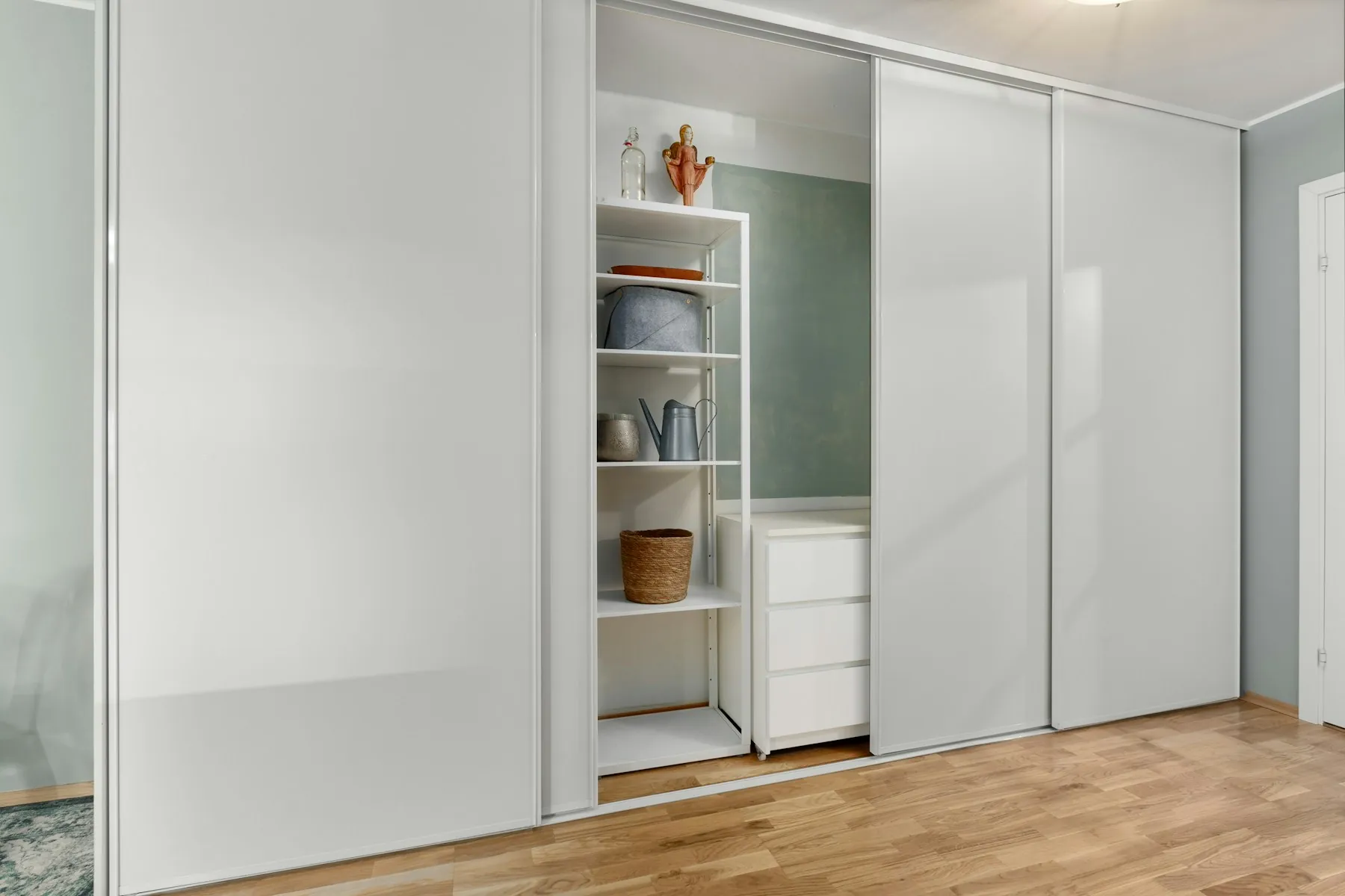 White floor-to-ceiling sliding wardrobe with one door open to shelves inside